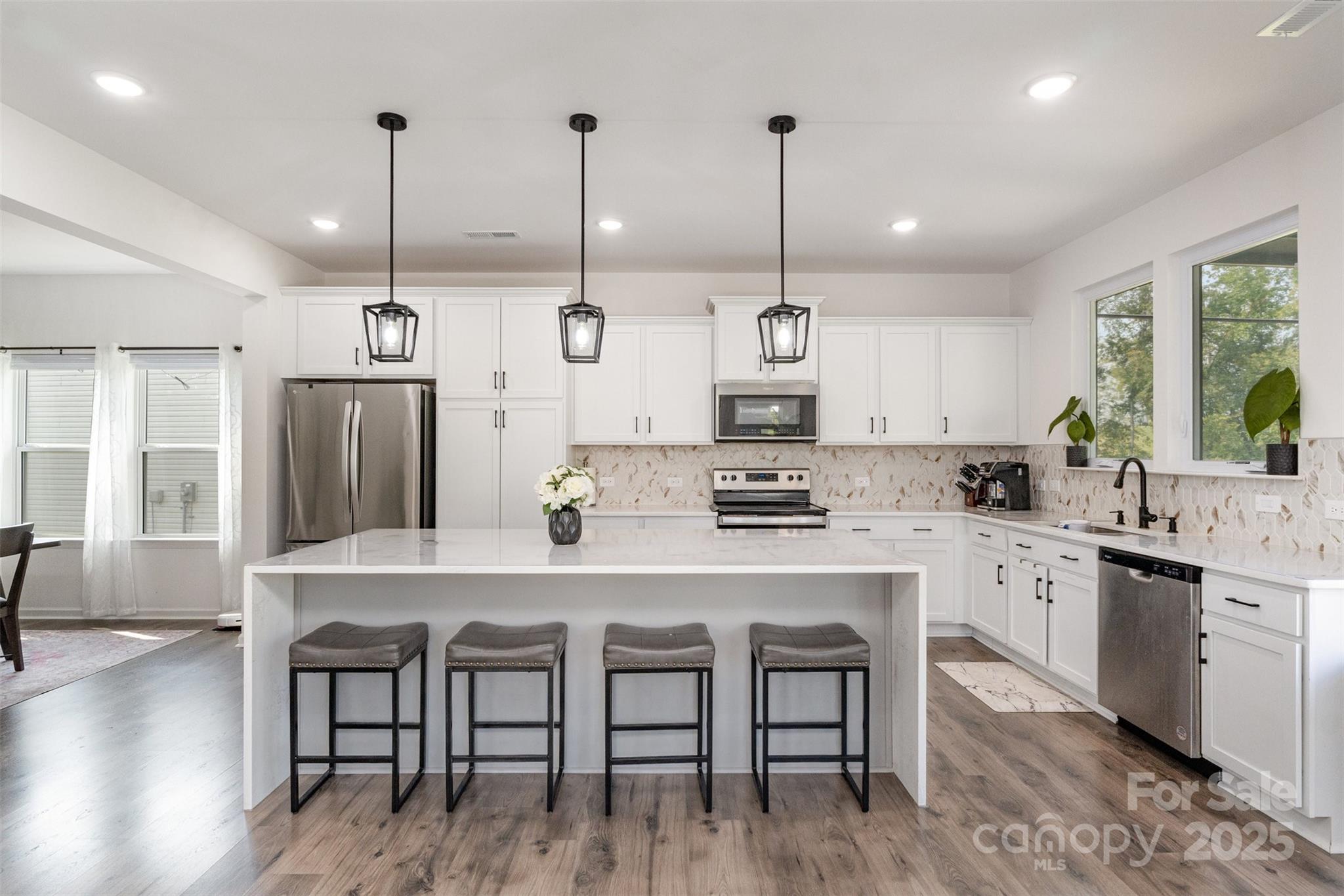3127 Pinehills Wy. Mount Holly, NC 28120 - Photo 7 of 35 a kitchen with stainless steel appliances granite countertop a stove a refrigerator a kitchen island a sink and white cabinets with wooden floor