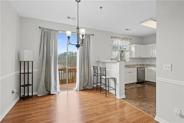 a kitchen with granite countertop a stove a sink dishwasher a refrigerator and a dining table with wooden floor