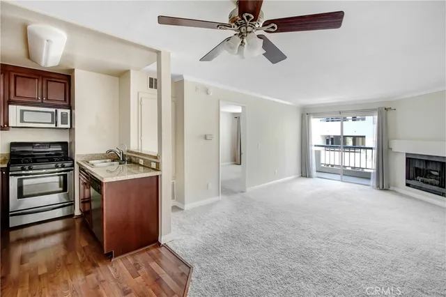 a view of a kitchen with a stove cabinets a ceiling fan and wooden floor