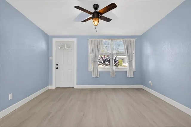 an empty room with windows and fan