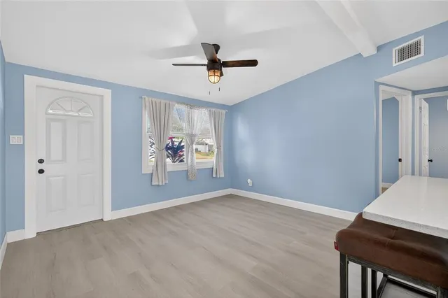 a view of an empty room with window and wooden floor
