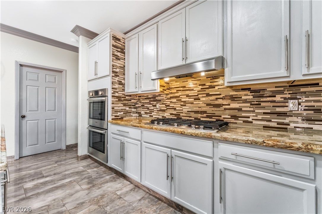 418 Finch Ridge Avenue North Las Vegas, NV 89032 - Photo 18 of 43 Kitchen with crown molding, light stone counters, stainless steel appliances, and white cabinetry