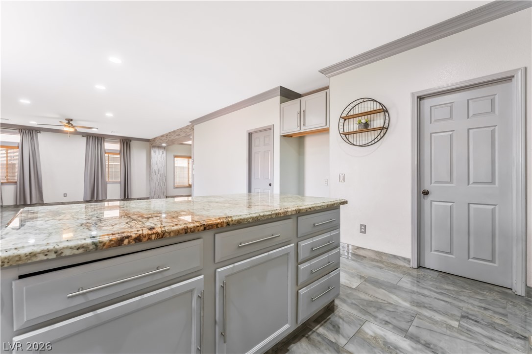 418 Finch Ridge Avenue North Las Vegas, NV 89032 - Photo 20 of 43 Kitchen with light stone countertops, crown molding, ceiling fan, gray cabinetry, and recessed lighting