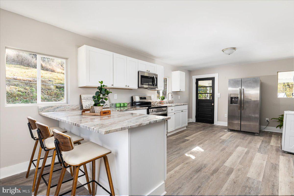 13886 Crest Hill Road Flint Hill, VA 22627 - Photo 11 of 45 a kitchen with stainless steel appliances granite countertop a stove a refrigerator a sink a dining table and chairs with wooden floor