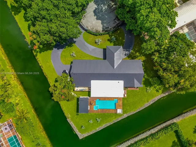 an aerial view of residential houses with outdoor space and trees