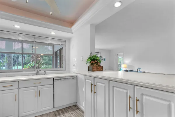 a kitchen with stainless steel appliances granite countertop a white refrigerator a sink and white cabinets