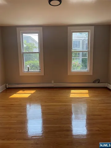 a view of empty room with window and wooden floor