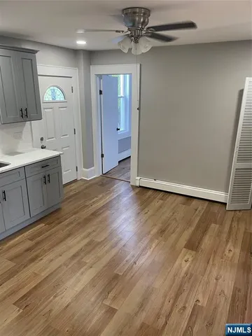 an empty room with wooden floor and a refrigerator