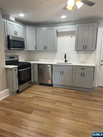 a large kitchen with granite countertop a stove top oven a sink and dishwasher wooden cabinets