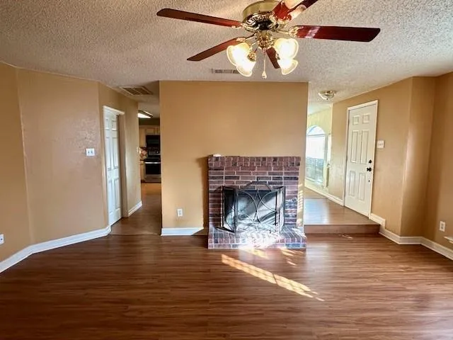 a view of a livingroom with a fireplace a chandelier and wooden floor