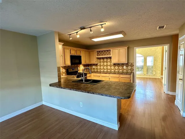 a view of a kitchen with kitchen island a sink wooden floor and a large window