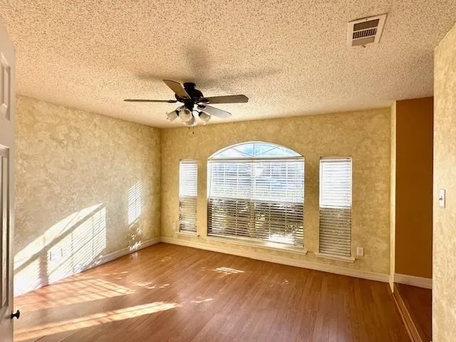 a view of an empty room with a window and wooden floor