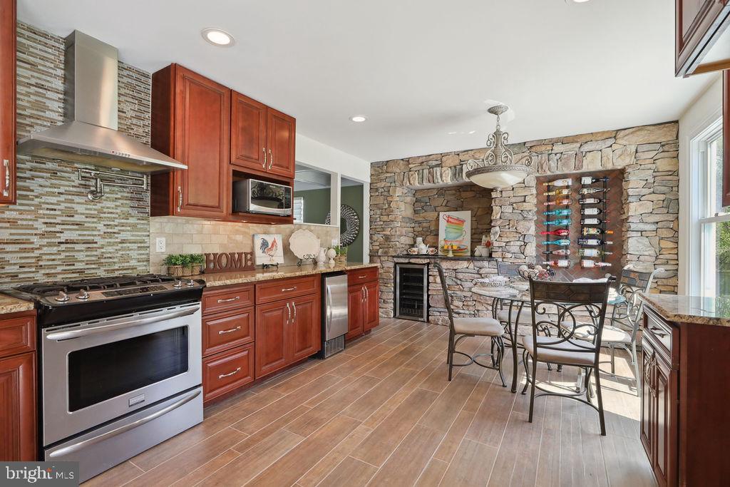 a kitchen with stainless steel appliances wooden floors wooden cabinets dining table and chair