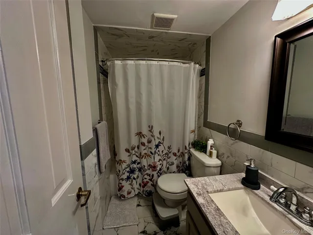 a bathroom with a sink a toilet a mirror and shower curtain