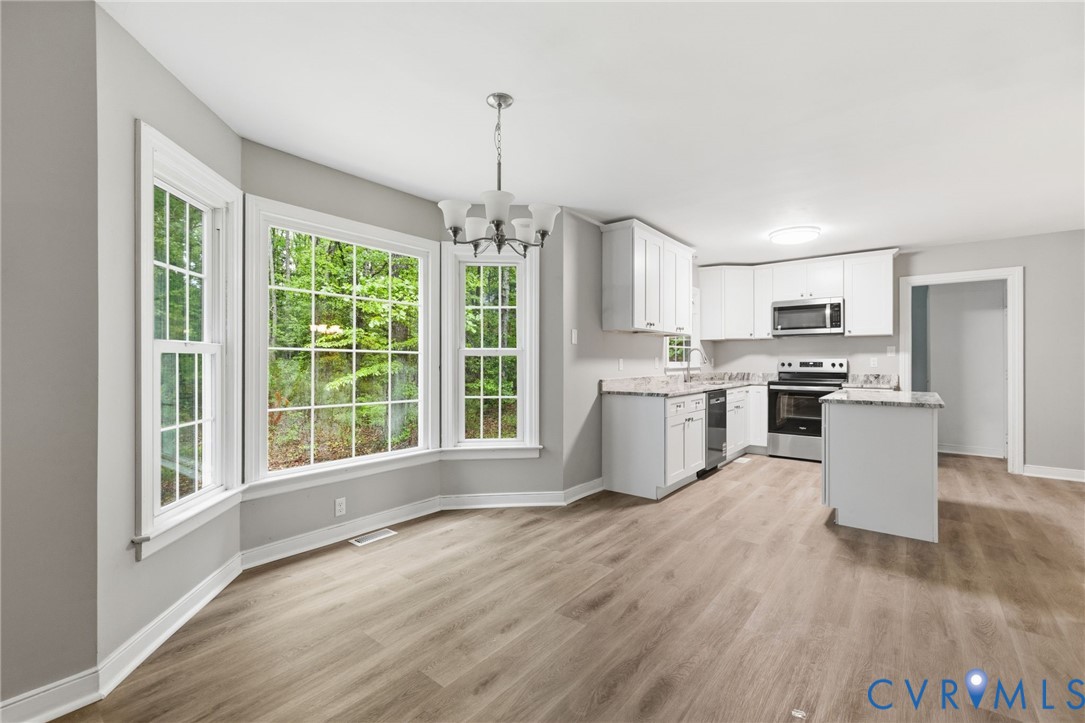 10731 Spring Run Road Chesterfield, VA 23832 - Photo 14 of 33 a kitchen with stainless steel appliances granite countertop a stove top oven a sink dishwasher a refrigerator and white cabinets with wooden floor