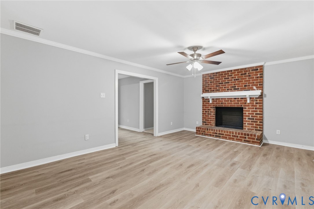 10731 Spring Run Road Chesterfield, VA 23832 - Photo 15 of 33 an empty room with wooden floor a ceiling fan and a fireplace