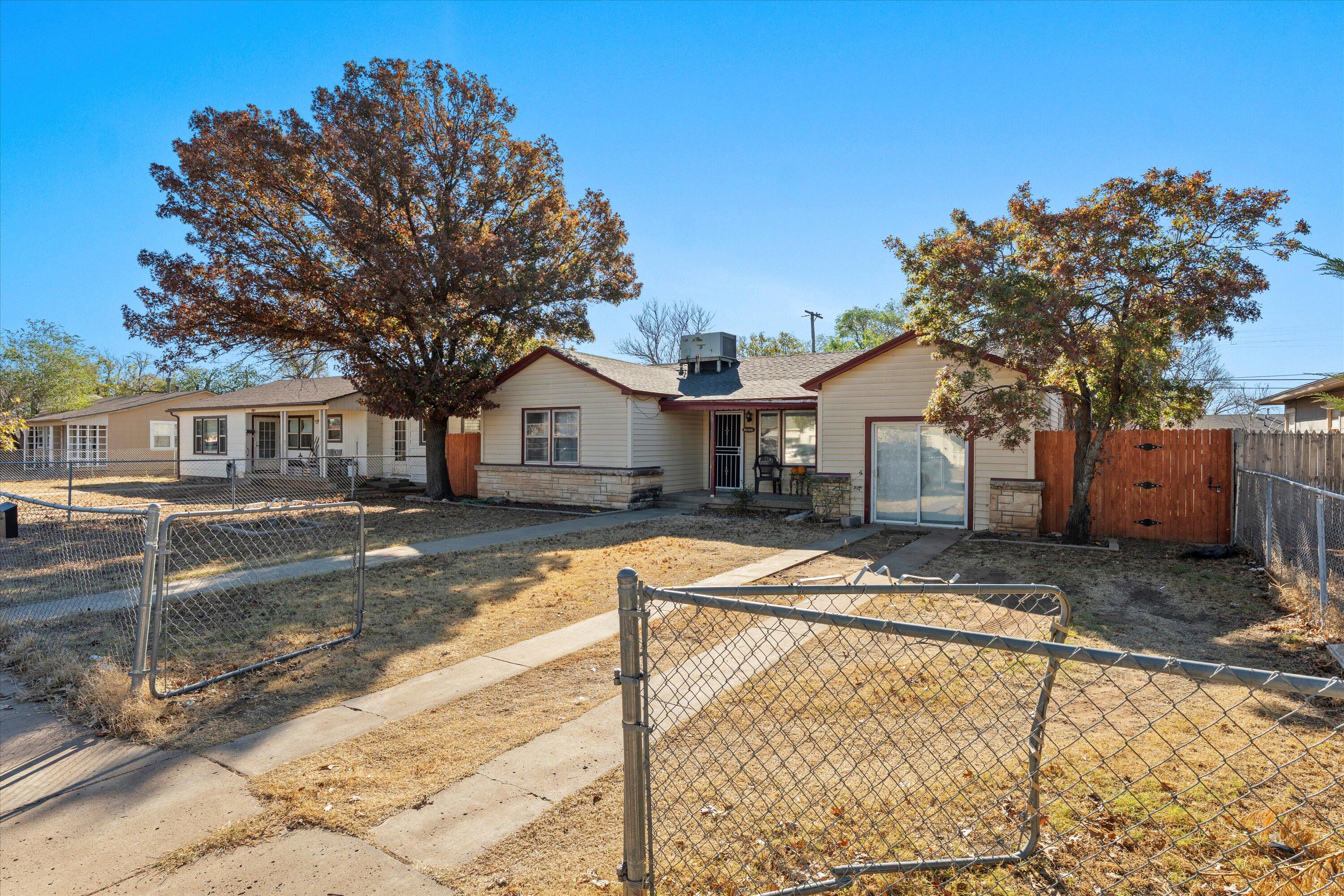 1915 37th Street Lubbock, TX 79412 - Photo 2 of 20 a view of a white house with a large tree with wooden fence