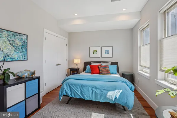 a bedroom with a bed a dresser and next to a window