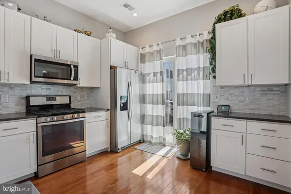 a kitchen with cabinets stainless steel appliances and wooden floor