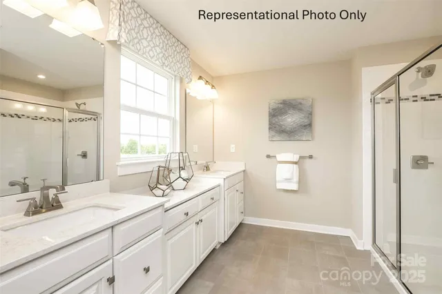 a spacious bathroom with double vanity a mirror and a shower