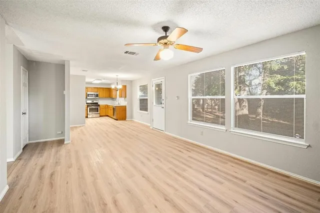 a view of an empty room with a window and wooden floor