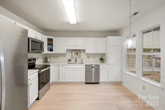 a kitchen with granite countertop a sink a counter top space stainless steel appliances and cabinets