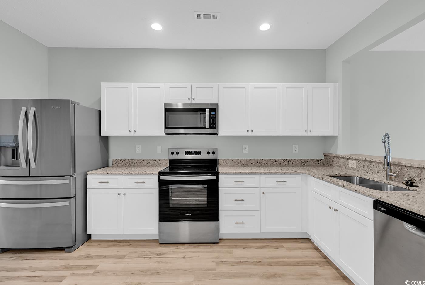 308 Kiskadee Loop, Unit E Conway, SC 29526 - Photo 10 of 36 Kitchen featuring appliances with stainless steel finishes, light stone counters, white cabinets, light wood-style floors, and recessed lighting