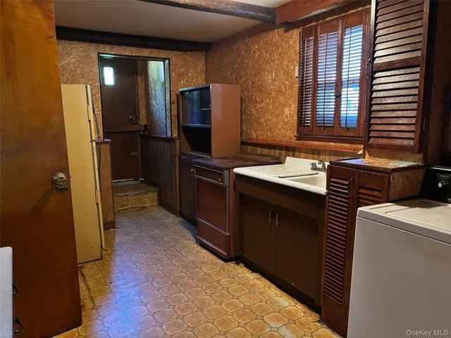 a view of a refrigerator in kitchen and an empty room