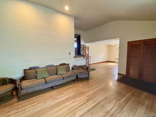 a living room with couches and kitchen view with wooden floor