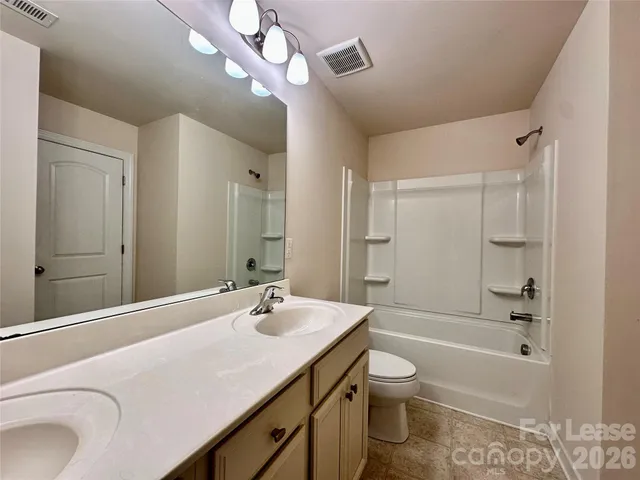 an empty room with a chandelier fan and windows