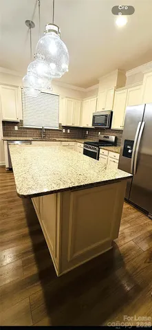 a kitchen with stainless steel appliances granite countertop a sink a stove a refrigerator a center island and cabinets