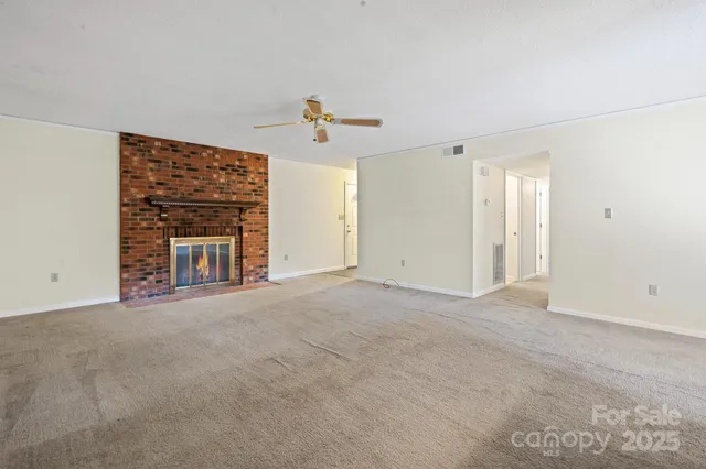 a view of an empty room with a fireplace and a window