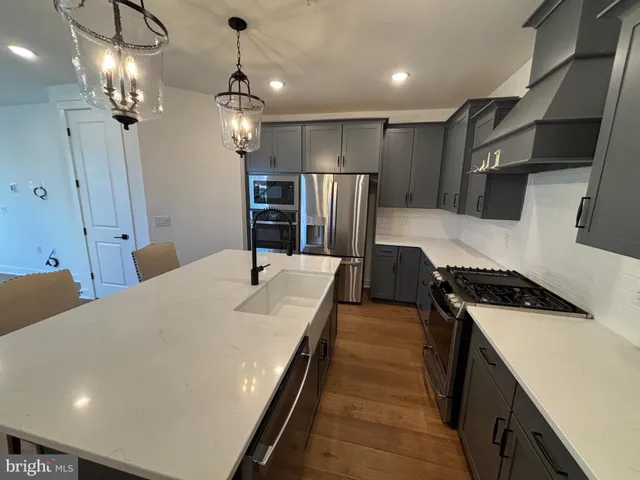 a kitchen with kitchen island a counter top space a sink stainless steel appliances and cabinets