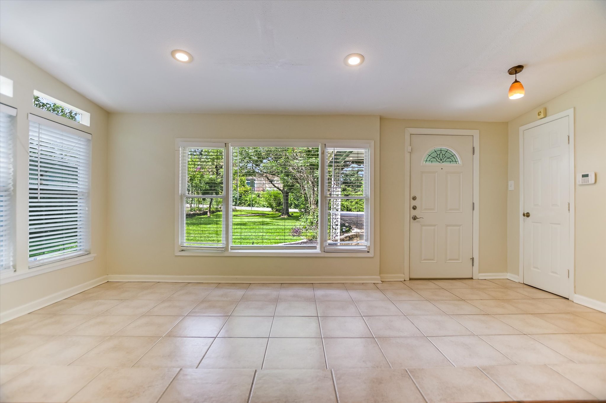 208 Braeswood Road Austin, TX 78704 - Photo 4 of 20 A welcoming entry features a paneled front door and large windows overlooking lush greenery.