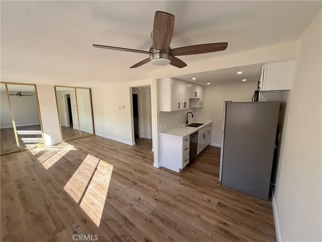 a open kitchen with stainless steel appliances granite countertop a refrigerator a stove and a wooden floors