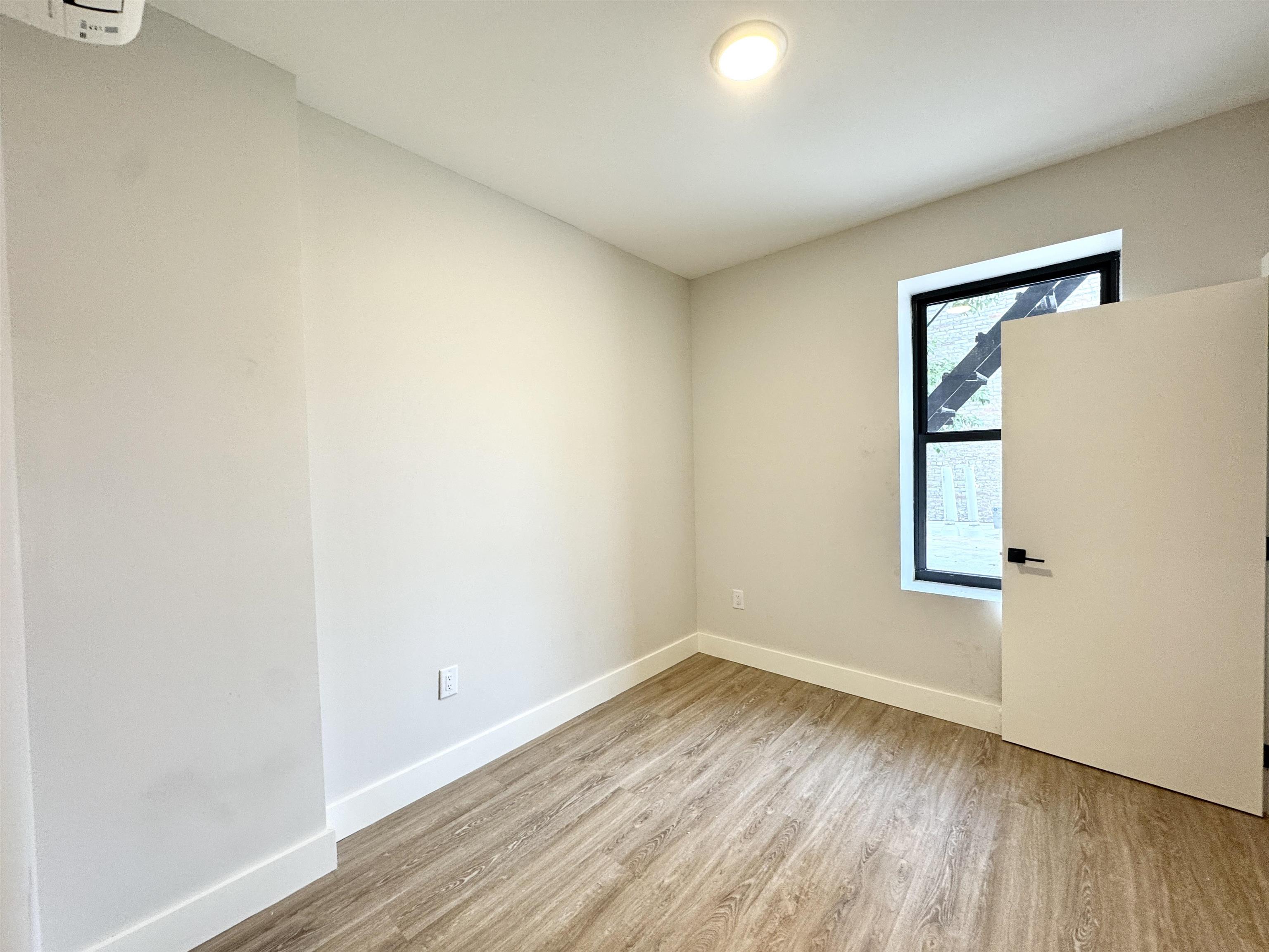 103 Bostwick Avenue, Unit 2C Jersey City, NJ 07305 - Photo 3 of 11 an empty room with wooden floor and windows