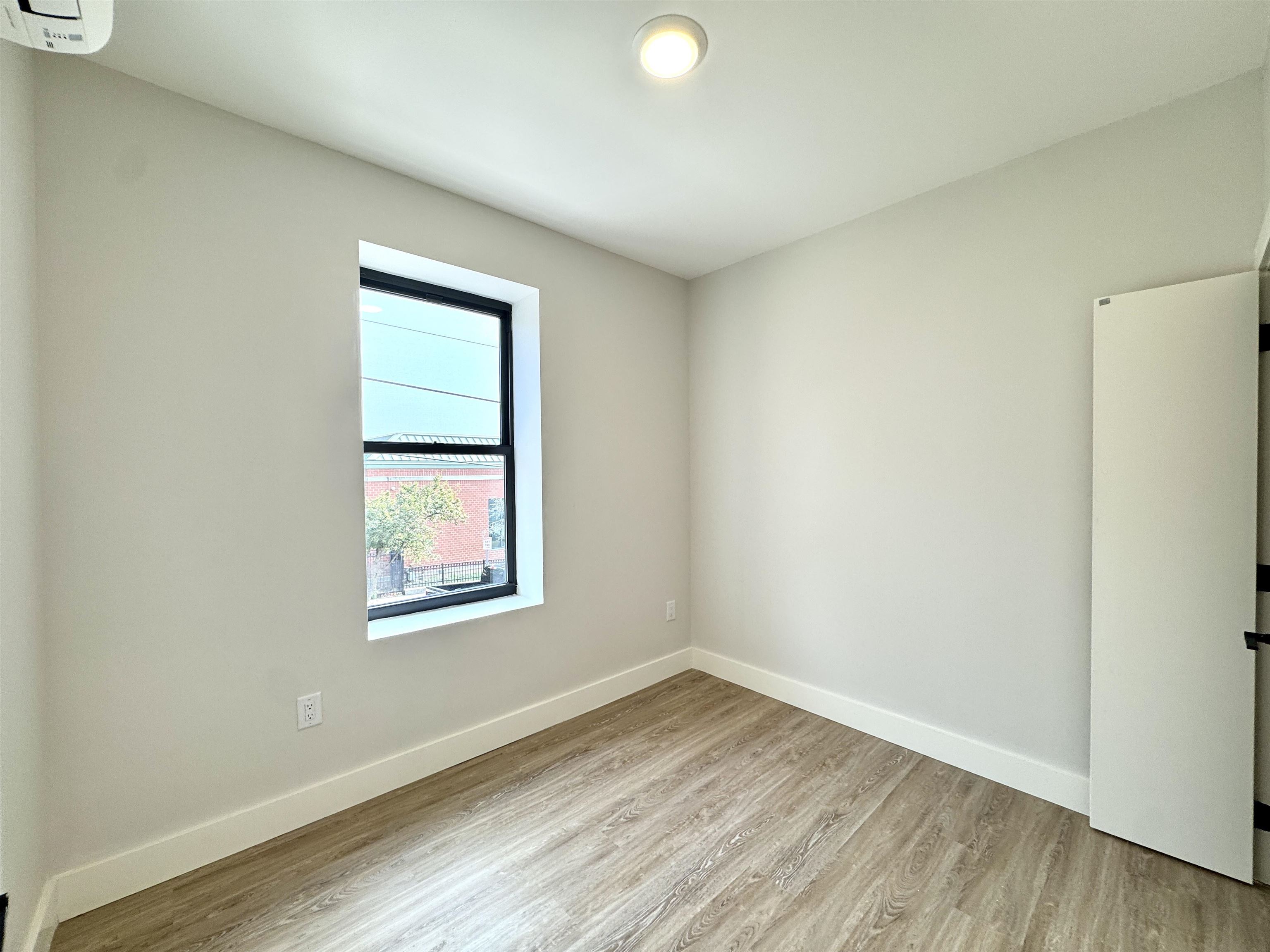 103 Bostwick Avenue, Unit 2C Jersey City, NJ 07305 - Photo 8 of 11 an empty room with wooden floor and windows