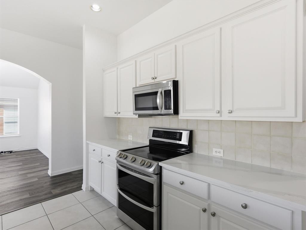 424 Shady Shore Lane Crowley, TX 76036 - Photo 17 of 40 a kitchen with white cabinets and stainless steel appliances