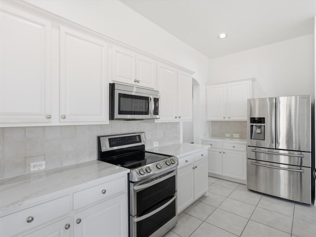 424 Shady Shore Lane Crowley, TX 76036 - Photo 18 of 40 a kitchen with white cabinets and stainless steel appliances