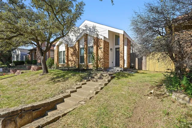 a view of a house with a yard and large tree