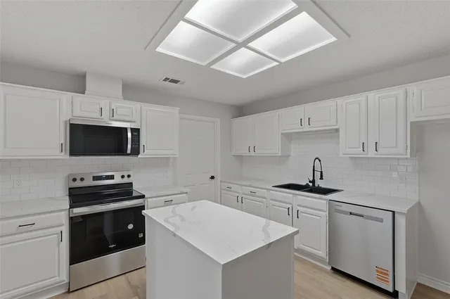 a kitchen with white cabinets and stainless steel appliances