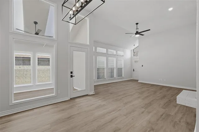 a view of empty room with wooden floor and ceiling fan