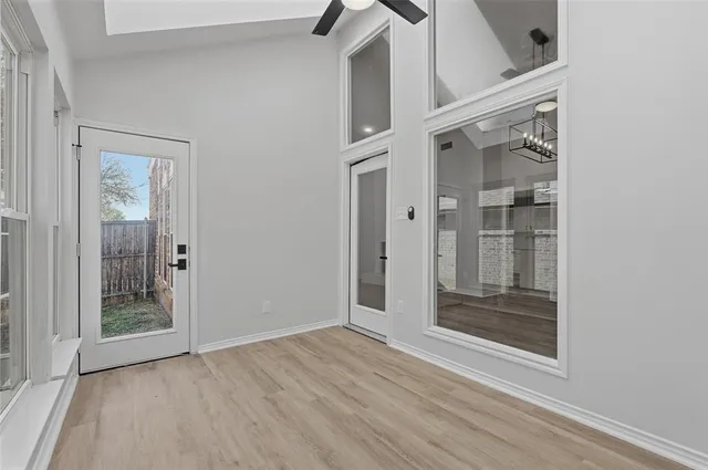 an empty room with wooden floor mirror and windows