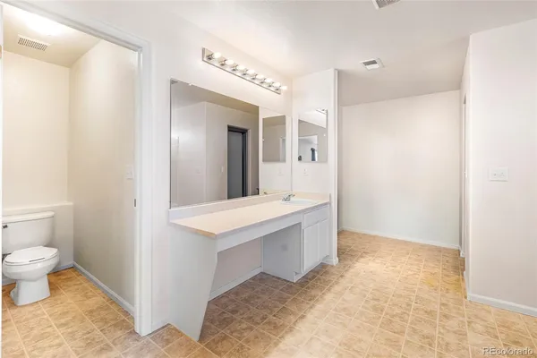 a spacious bathroom with a sink a toilet and a mirror