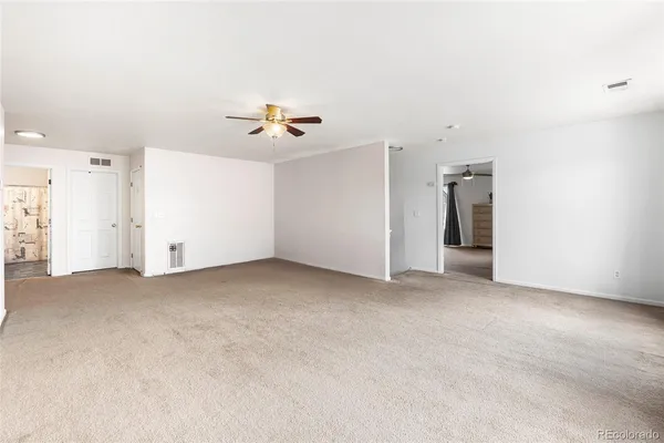an empty room with chandelier fan and windows