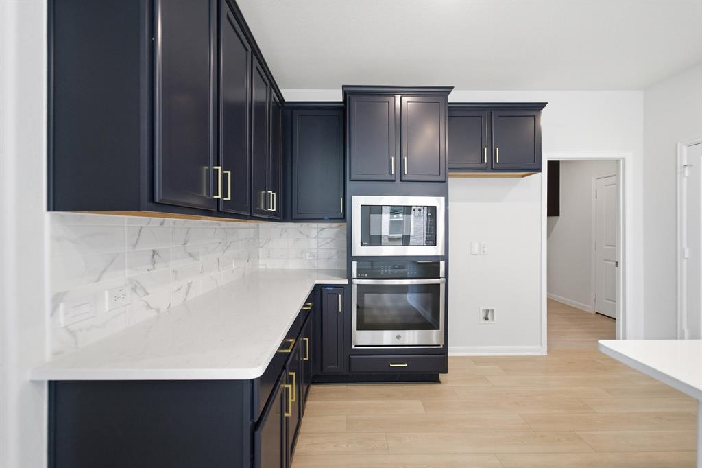 1908 Sangallo Lane Celina, TX 75009 - Photo 23 of 35 Kitchen featuring dark cabinetry with gold-finish hardware, white countertops, tile backsplash, built-in stainless steel microwave, and built-in stainless steel oven