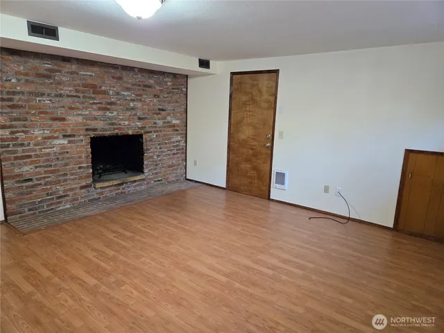 a view of empty room with wooden floor and fireplace