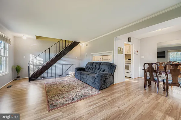 a living room with furniture and a dining table with wooden floor