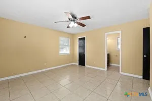 a view of an empty room with window and chandelier fan