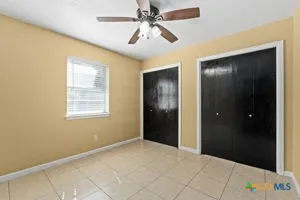 an empty room with closet and a chandelier fan